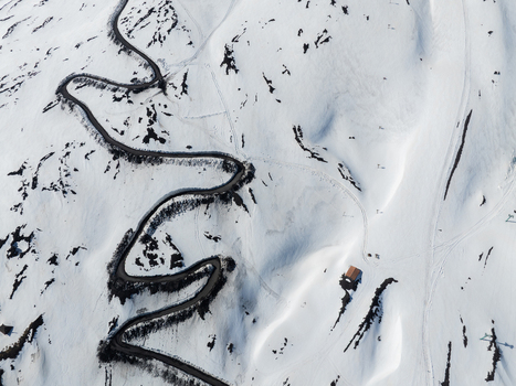 Aerial view of the winding road on the Versante sud dell Etna covered in white snow with dark volcanic rocks in Nicolosi Sicilia Italy. Aerial view of the winding road on the Versante sud dell Etna covered in white snow with dark volcanic rocks in Nicolosi Sicilia Italy.