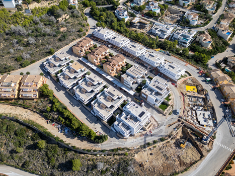 Aerial view of a modern residential development in Moraira featuring white villas with flat roofs swimming pools and landscaped gardens Moraira Valencian Community Spain.