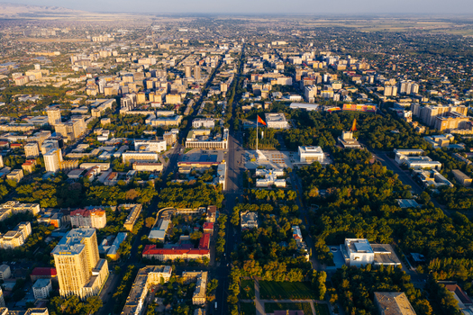Aerial view of the city center featuring Ala Too Square and the national flag surrounded by lush green parks and urban architecture in Bishkek Bishkek City Kyrgyzstan.