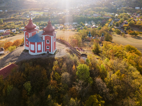 Aerial view of Stiavnica Calvary a historic pilgrimage site with red roofed churches on a hill surrounded by autumn forests in Banska Stiavnica Banskobystricky kraj Slovakia. Aerial view of Stiavnica Calvary a historic pilgrimage site with red roofed churches on a hill surrounded by autumn forests in Banska Stiavnica Banskobystricky kraj Slovakia.