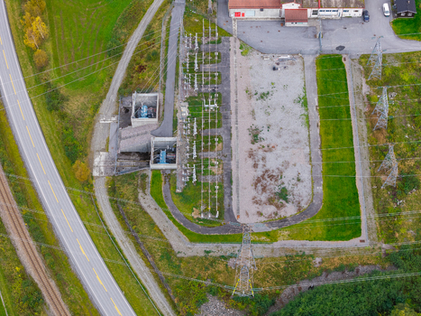 Aerial view of an electrical substation with power lines transformers and adjacent road and railway tracks in Andalsnes More og Romsdal Norway. Aerial view of an electrical substation with power lines transformers and adjacent road and railway tracks in Andalsnes More og Romsdal Norway.