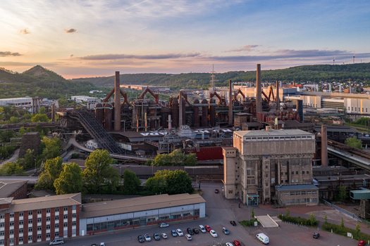 Volklingen Germany 09 May 2026 Aerial view of the Volklingen Ironworks industrial complex with its blast furnaces and chimneys under a sunset sky and green hills. Volklingen Germany 09 May 2026 Aerial view of the Volklingen Ironworks industrial complex with its blast furnaces and chimneys under a sunset sky and green hills.