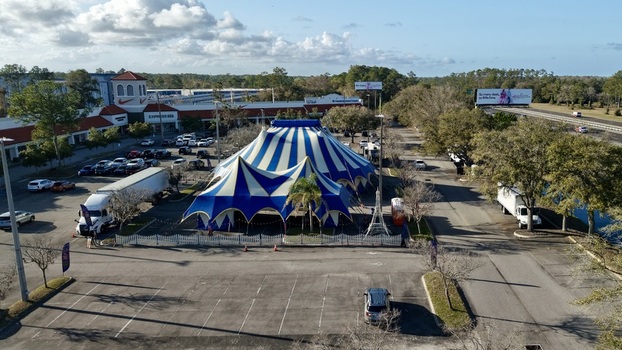 Aerial view of the grand blue and white striped circus tent standing proudly amidst a sea of parked cars framed by the distant shops and highway St. Augustine Florida United States. Aerial view of the grand blue and white striped circus tent standing proudly amidst a sea of parked cars framed by the distant shops and highway St. Augustine Florida United States.