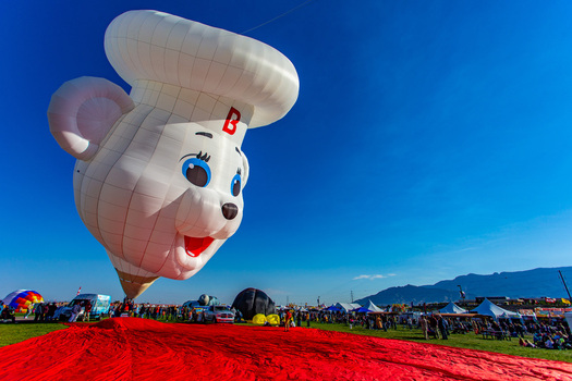 Albuquerque United States 09 October 2017 View of a whimsical oversized balloon shaped like a chef hatted mouse its jovial smile set against a brilliant blue sky above a crowd of onlookers.