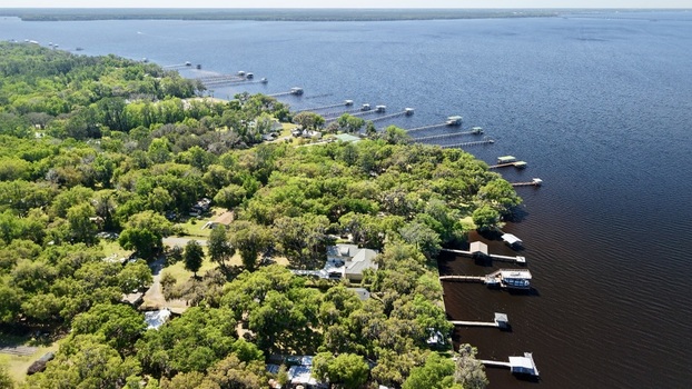 Aerial view of Sixmile Creek featuring wooden docks extending into the dark water and lush green forest in St. Johns County Florida United States.