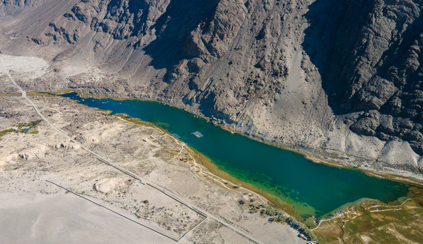 Aerial view of Blind Lake Sarfaranga Shigar nestled among arid rocky mountains with turquoise waters and sparse vegetation in Skardu Gilgit Pakistan.