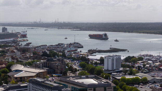 Aerial view of the port of Southampton with a large container ship cruise ships and harbor facilities surrounded by urban infrastructure in Southampton England United Kingdom. Aerial view of the port of Southampton with a large container ship cruise ships and harbor facilities surrounded by urban infrastructure in Southampton England United Kingdom.