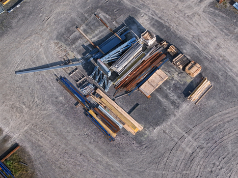 Aerial view of an industrial yard with stacks of steel beams timber planks and construction materials on gravel ground in Melbourne VIC Australia. Aerial view of an industrial yard with stacks of steel beams timber planks and construction materials on gravel ground in Melbourne VIC Australia.
