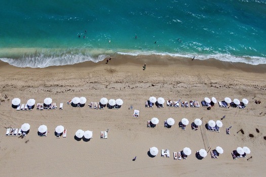 Aerial view of Singer Island beach with turquoise water white umbrellas and people relaxing on the sand Riviera Beach Florida United States. Aerial view of Singer Island beach with turquoise water white umbrellas and people relaxing on the sand Riviera Beach Florida United States.