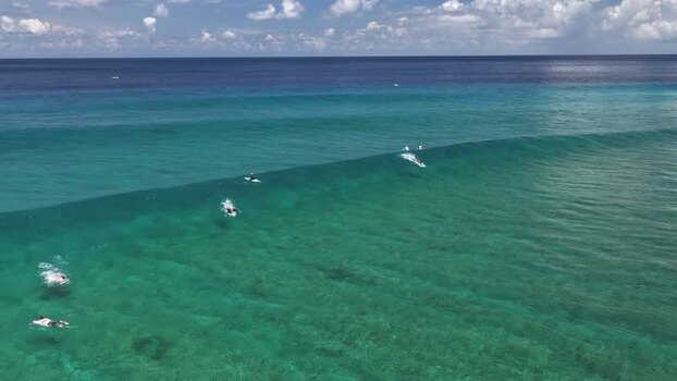 Aerial view of surfers riding a turquoise wave in Thulusdhoo Maldives. Aerial view of surfers riding a turquoise wave in Thulusdhoo Maldives.