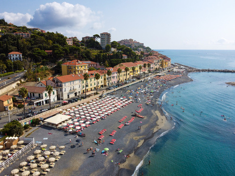 Aerial view of the sandy beach with colorful umbrellas and historic buildings along the coastline in Imperia Liguria Italy. Aerial view of the sandy beach with colorful umbrellas and historic buildings along the coastline in Imperia Liguria Italy.