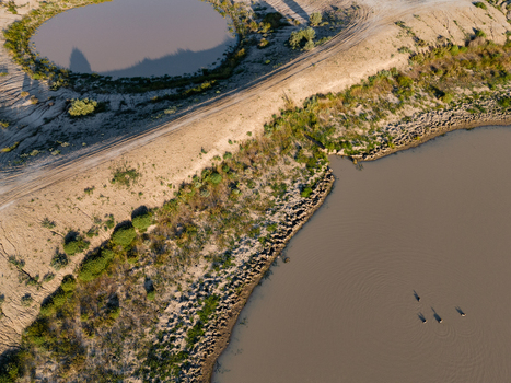Aerial view of a flat landscape featuring muddy water ponds dirt tracks and sparse vegetation in Hay New South Wales Australia.