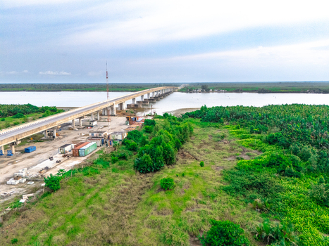 Aerial view of the bridge spanning the river with lush greenery and construction site containers in Bonny Town Rivers Nigeria. Aerial view of the bridge spanning the river with lush greenery and construction site containers in Bonny Town Rivers Nigeria.