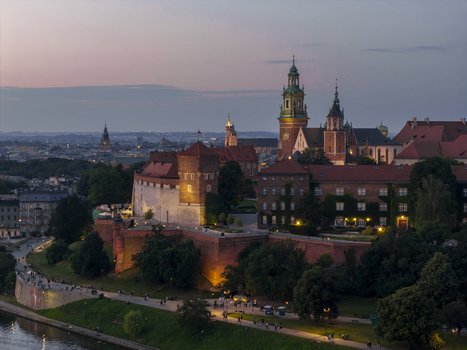 Aerial view of Wawel Castle with its historic fortifications towers and cathedral illuminated at dusk along the Vistula River in Krakow Lesser Poland Voivode Poland. Aerial view of Wawel Castle with its historic fortifications towers and cathedral illuminated at dusk along the Vistula River in Krakow Lesser Poland Voivode Poland.