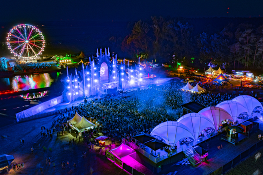 Herzogenaurach Germany 22 July 2022 Aerial view of the Open Beatz Festival at night featuring a large illuminated stage a colorful ferris wheel and crowds of people. Herzogenaurach Germany 22 July 2022 Aerial view of the Open Beatz Festival at night featuring a large illuminated stage a colorful ferris wheel and crowds of people.