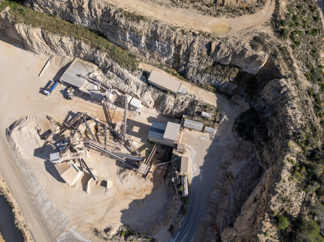 Aerial view of a stone quarry with industrial crushing machinery conveyor belts and trucks in Teulada Valencian Community Spain.