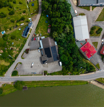 Aerial view of a commercial building with solar panels and a parking lot situated near a road and a lake in Zebrak Central Bohemian Region Czechia. Aerial view of a commercial building with solar panels and a parking lot situated near a road and a lake in Zebrak Central Bohemian Region Czechia.