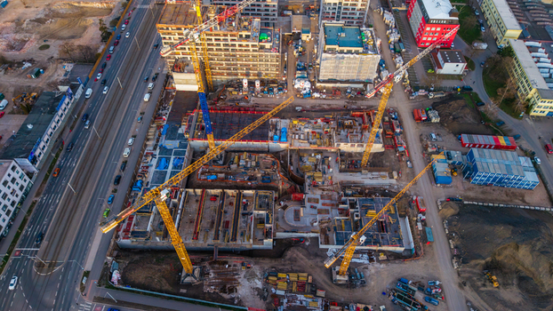 Aerial view of a construction site bustling with yellow cranes against the stark concrete foundations contrasting with the surrounding buildings Prague 9 Prague Czechia. Aerial view of a construction site bustling with yellow cranes against the stark concrete foundations contrasting with the surrounding buildings Prague 9 Prague Czechia.