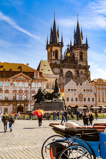 Prague Prague Czechia 08 May 2023 View of the Church of Our Lady before Tyn in the historic Old Town Square with cobblestones a horse drawn carriage and people under a blue sky. Prague Prague Czechia 08 May 2023 View of the Church of Our Lady before Tyn in the historic Old Town Square with cobblestones a horse drawn carriage and people under a blue sky.