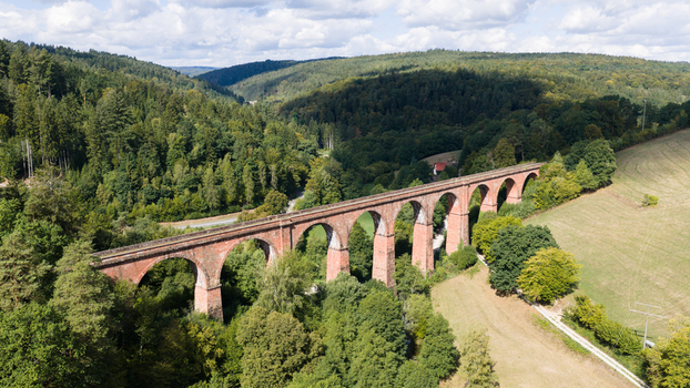Aerial view of the historic red brick Himbachel Viadukt bridge spanning a lush green valley surrounded by dense forests and rolling hills in Erbach Hessen Germany.