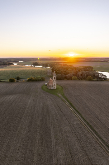 Aerial view of the historic Pusztatorony church ruins surrounded by vast agricultural fields at sunset in Somogyvamos Hungary. Aerial view of the historic Pusztatorony church ruins surrounded by vast agricultural fields at sunset in Somogyvamos Hungary.