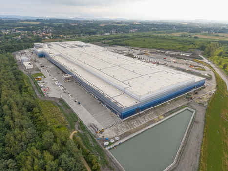 Aerial view of a large logistics hub with a flat roof blue and grey facade and loading docks situated near a retention pond in Skawina Lesser Poland Voivode Poland. Aerial view of a large logistics hub with a flat roof blue and grey facade and loading docks situated near a retention pond in Skawina Lesser Poland Voivode Poland.