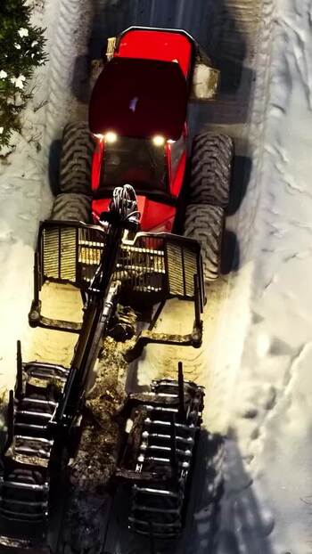 Aerial view of red forestry harvester in snowy forest Latvia.