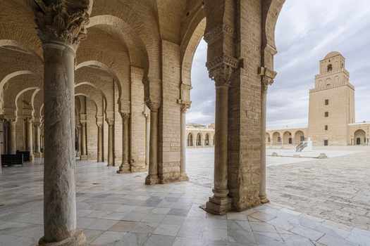 View of the Great Mosque of Kairouan with its historic stone columns arched portico and minaret in the courtyard in Kairouan Kairouan Governorate Tunisia.