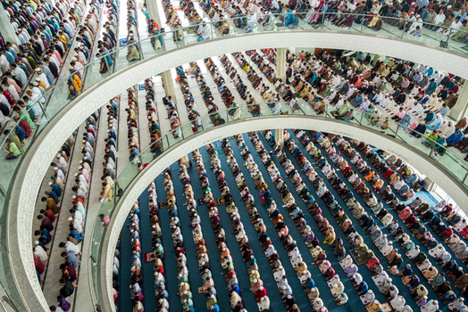 Dhaka Bangladesh 19 June 2026 Aerial view of a large crowd of men praying in rows inside a multi level mosque with modern architectural design and glass railings.