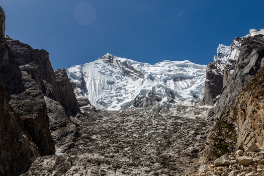 View of the Baltoro Glacier surrounded by rugged mountain peaks and rocky terrain under a clear blue sky in Baltoro Gilgit Baltistan Pakistan.