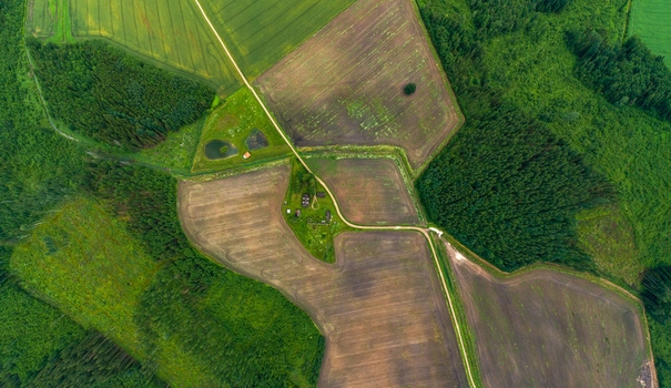 Aerial view of agricultural fields forests and a small farmstead with dirt roads and ponds in Latvia. Aerial view of agricultural fields forests and a small farmstead with dirt roads and ponds in Latvia.