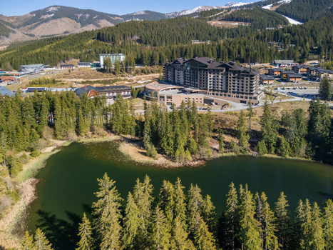Aerial view of DAMIAN JASNA Hotel Resort and Residences by a mountain lake surrounded by pine forests and the Low Tatras mountains in Demanovska Dolina Zilinsky kraj Slovakia. Aerial view of DAMIAN JASNA Hotel Resort and Residences by a mountain lake surrounded by pine forests and the Low Tatras mountains in Demanovska Dolina Zilinsky kraj Slovakia.