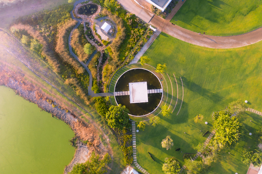 Aerial view of a modern landscaped garden featuring a circular pond with a central pavilion winding stone paths and lush green lawns under soft morning light Cape Town Western Cape South Africa. Aerial view of a modern landscaped garden featuring a circular pond with a central pavilion winding stone paths and lush green lawns under soft morning light Cape Town Western Cape South Africa.