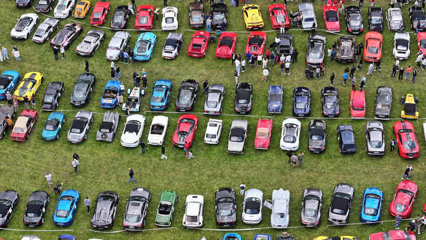 La Chapelle de Guinchay France 01 June 2024 Aerial view of rows of colorful luxury sports cars and vintage vehicles parked on a green field during an outdoor automotive event.