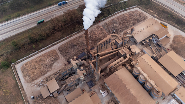 Aerial view of Kawasan Industri Terpadu Batang industrial facility with a smoking chimney large factory buildings and adjacent highway in Kecamatan Gringsing Jawa Tengah Indonesia.