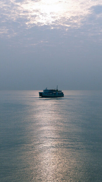 Aerial view of a ferry boat sailing on the calm sea under a soft hazy sky in Dumaguete City Negros Island Region Philippines. Aerial view of a ferry boat sailing on the calm sea under a soft hazy sky in Dumaguete City Negros Island Region Philippines.