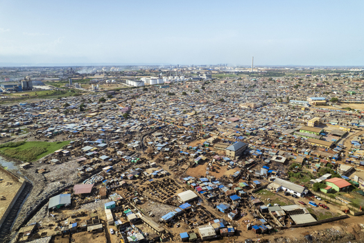 Aerial view of sprawling settlements contrasting with industrial structures under a pale sky creating a panorama of urban life Tema Ghana. Aerial view of sprawling settlements contrasting with industrial structures under a pale sky creating a panorama of urban life Tema Ghana.