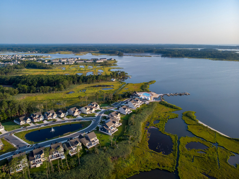 Ocean City Maryland United States 28 July 2019 Aerial view of a coastal residential neighborhood with modern houses a central pond and surrounding wetlands near the bay.