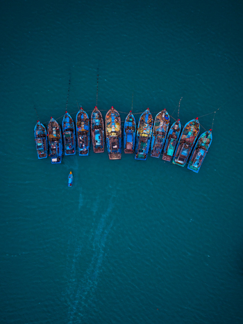 Aerial view of a fleet of colorful fishing boats moored in deep blue sea water in Vietnam. Aerial view of a fleet of colorful fishing boats moored in deep blue sea water in Vietnam.