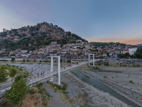 Aerial view of the historic Gorica Bridge in Berat with traditional Ottoman style houses on the hillside the Osum River and people walking across the bridge in Berat Berat County Albania.