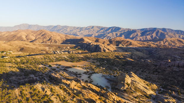 Aerial view of rugged rock formations and desert landscape with sparse vegetation under a clear sky in the United States. Aerial view of rugged rock formations and desert landscape with sparse vegetation under a clear sky in the United States.