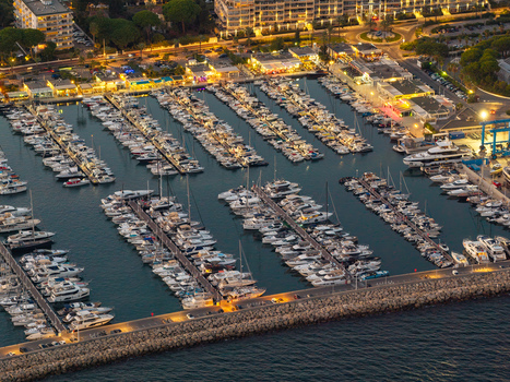 Aerial view of Port Vauban marina filled with yachts and boats docked at piers during the evening with city lights in Antibes Provence Alpes Cote d Azur France. Aerial view of Port Vauban marina filled with yachts and boats docked at piers during the evening with city lights in Antibes Provence Alpes Cote d Azur France.
