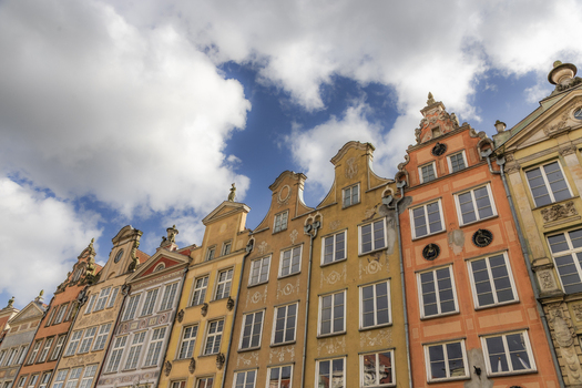 View of colorful historic tenement houses with ornate gables under a cloudy blue sky in Gdansk Pomeranian Voivodeship Poland. View of colorful historic tenement houses with ornate gables under a cloudy blue sky in Gdansk Pomeranian Voivodeship Poland.