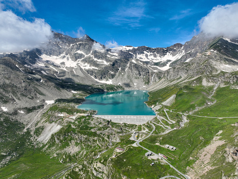 Aerial view of Serru Lake with its turquoise water and concrete dam surrounded by the rugged snow capped peaks of the Graian Alps in Ceresole Reale Piedmont Italy. Aerial view of Serru Lake with its turquoise water and concrete dam surrounded by the rugged snow capped peaks of the Graian Alps in Ceresole Reale Piedmont Italy.