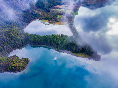 Aerial view of Lagoa do Fogo surrounded by lush green volcanic slopes and misty clouds reflecting on the turquoise water in Agua de Alto Azores Portugal. Aerial view of Lagoa do Fogo surrounded by lush green volcanic slopes and misty clouds reflecting on the turquoise water in Agua de Alto Azores Portugal.