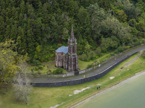 Aerial view of Ermida de Nossa Senhora das Vitorias a Gothic revival chapel nestled in lush forest beside the lake with a stone wall and path in Furnas Acores Portugal. Aerial view of Ermida de Nossa Senhora das Vitorias a Gothic revival chapel nestled in lush forest beside the lake with a stone wall and path in Furnas Acores Portugal.