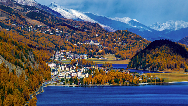 Saint Moritz Grisons Switzerland 24 October 2025 Aerial view of the town of Saint Moritz nestled by the lake surrounded by vibrant autumn larch forests and snow capped mountains.