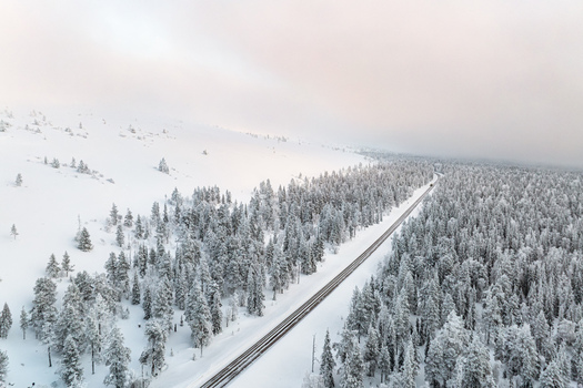 Aerial view of the snow covered Yllas fell landscape with a road winding through a dense frost covered pine forest in Kolari Lapland Finland. Aerial view of the snow covered Yllas fell landscape with a road winding through a dense frost covered pine forest in Kolari Lapland Finland.