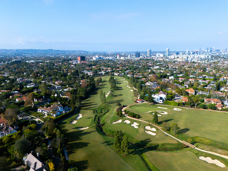 Aerial view of Wilshire Country Club golf course with green fairways sand bunkers and surrounding residential neighborhood in Los Angeles California United States. Aerial view of Wilshire Country Club golf course with green fairways sand bunkers and surrounding residential neighborhood in Los Angeles California United States.