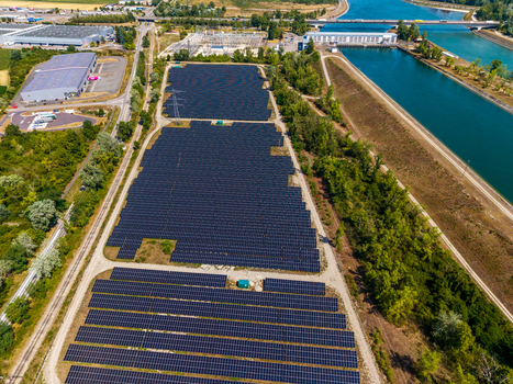 Aerial view of the Solarfeld solar farm with rows of photovoltaic panels situated next to a canal and industrial buildings in Hombourg Grand Est France.